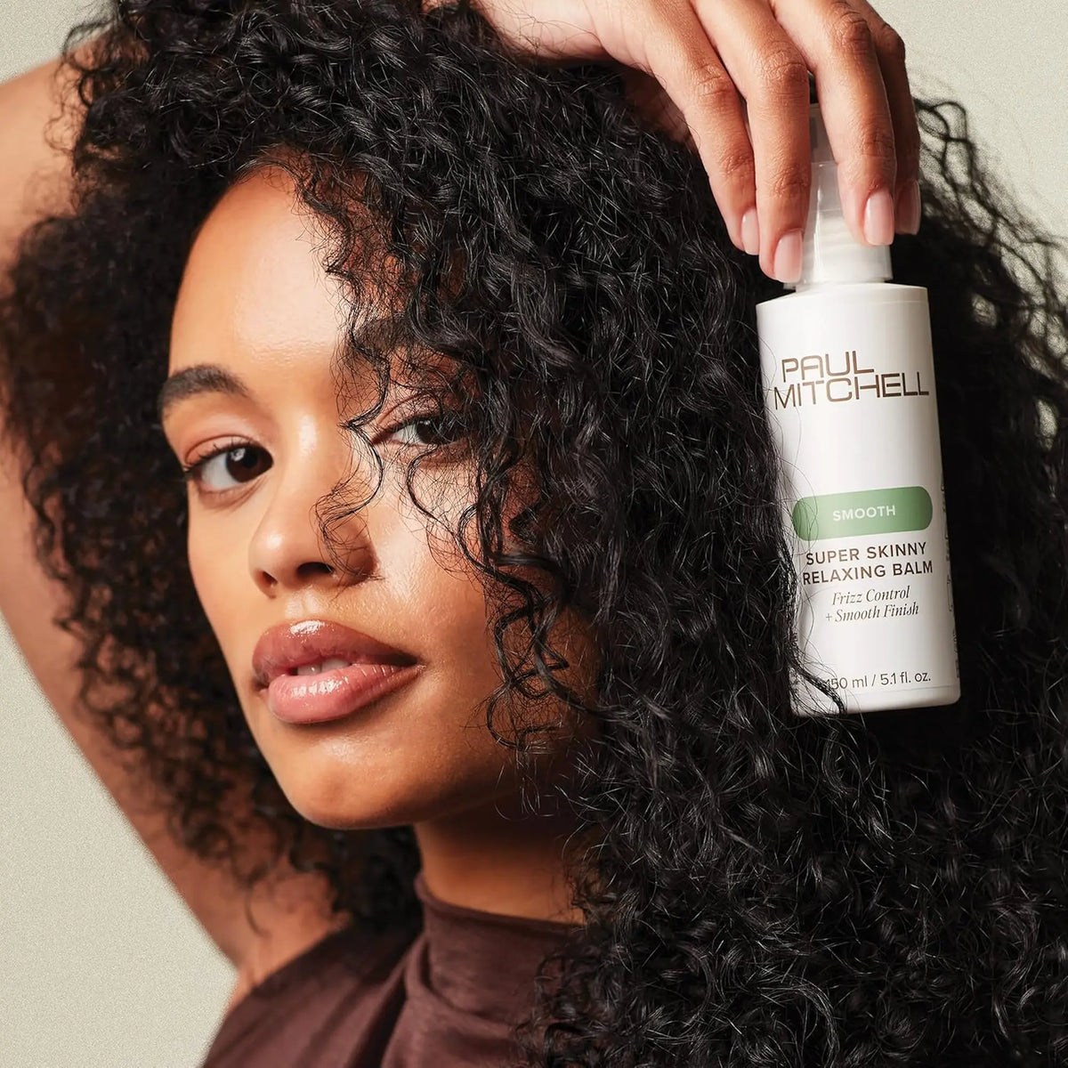 Flacon pompe de baume lissant Paul Mitchell Super Skinny Relaxing Balm : blanc avec étiquette verte, pour contrôler les frisottis, lisser les cheveux bouclés/texturés et protéger de la chaleur.
