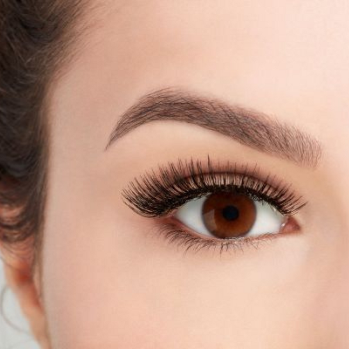 Boîtier transparent de la marque Ardell, modèle Natural 105. Les faux-cils noirs sont posés sur un support blanc, montrant une bande invisible transparente pour un effet naturel.