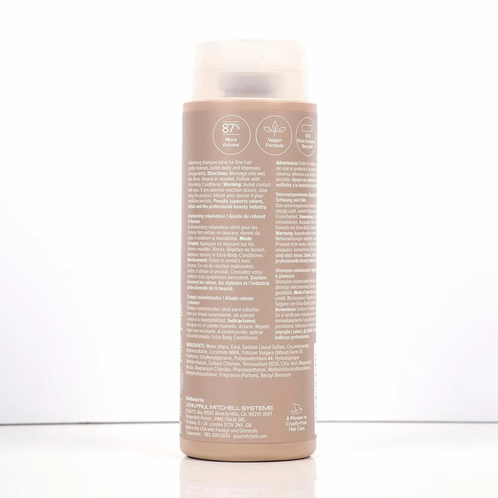 Bouteille beige de shampoing Paul Mitchell Extra-Body : étiquette mauve, pour ajouter du volume, du rebond et de la plénitude aux cheveux fins ou normaux.