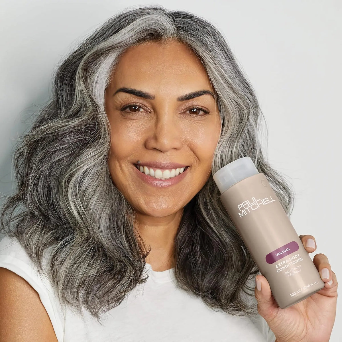 Bouteille beige de revitalisant Paul Mitchell Extra-Body  300ml : étiquette mauve, pour ajouter du rebond et de la plénitude aux cheveux fins ou normaux.